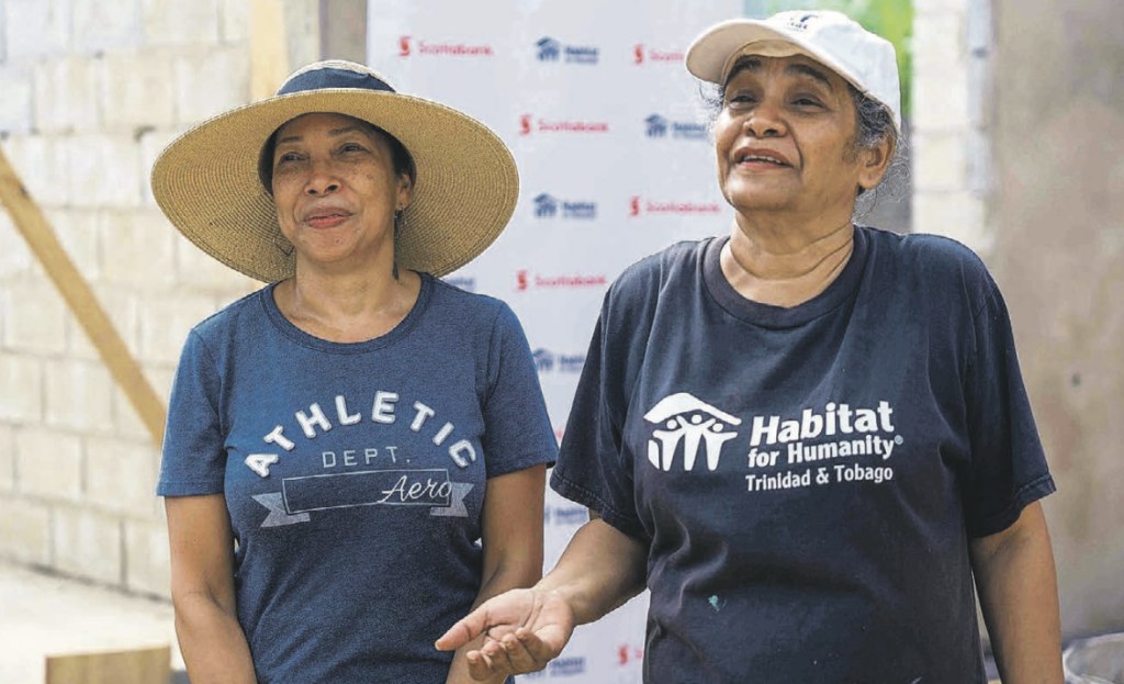 Sharon Da Silva, recipient of the home being constructed, left, and Carlene Pooran, resource development co-ordinator, Habitat for Humanity TT, right, welcome Scotiabank volunteers. -